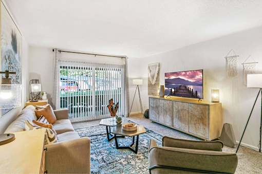 A living room with a large screen TV and a couch at The Waverly on the Lake - Belleville, MI Apartment , Belleville