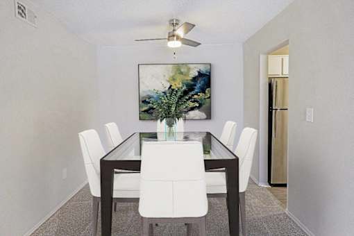 A dining room with a table and chairs and a painting on the wall at The Waverly on the Lake - Belleville, MI Apartment , Michigan, 48111
