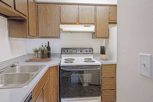 A modern kitchen with wooden cabinets and stainless steel appliances at The Waverly on the Lake - Belleville, MI Apartment, Belleville, MI, 95050