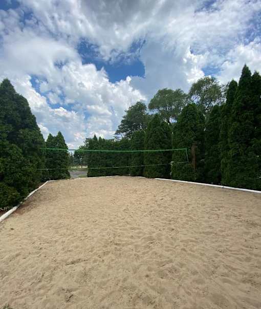 A sandy volleyball court surrounded by trees.