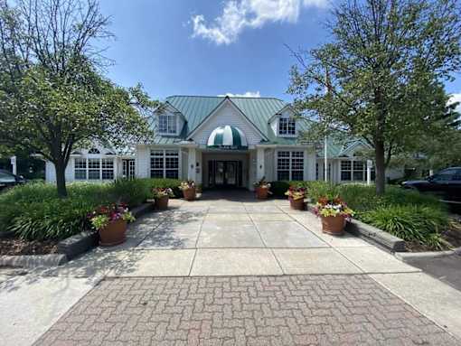 A white building with a green roof and a brick walkway in front.
