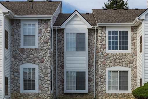A row of houses with white siding and stone accents.