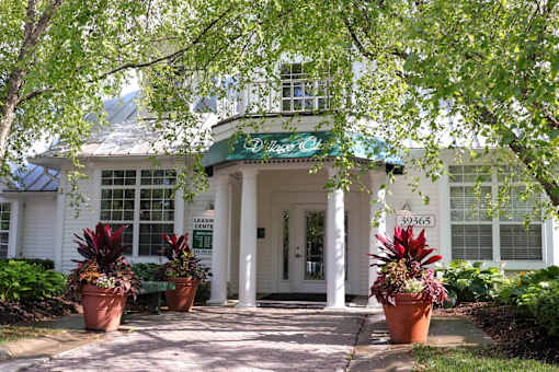 A white building with a green awning and a sign that says "The Oaks".