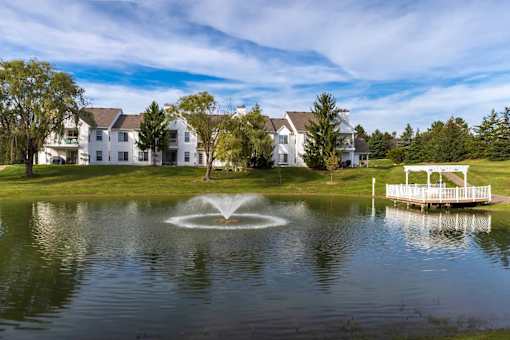 A fountain in the middle of a lake in front of a white building.