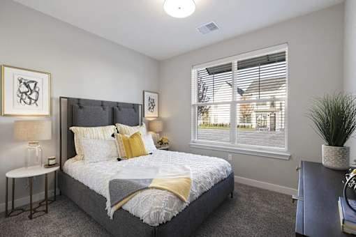 A bedroom with a large bed and a window with blinds.
