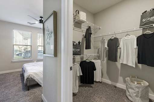 A bedroom with a bed, a window, and a closet with clothes.