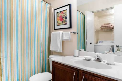 A bathroom with a striped shower curtain and a white toilet.