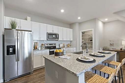 A modern kitchen with a granite countertop and stainless steel appliances.