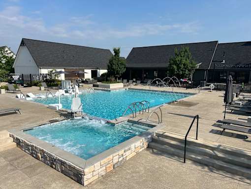 A large outdoor swimming pool with a hot tub and lounge chairs.