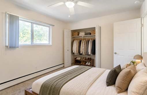 A bedroom with a bed, pillows, a closet, and a window.