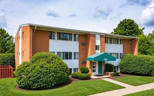 A building with a green awning and bushes in front.