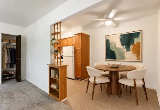A room with a brown table and chairs, a wooden cabinet, and a painting on the wall.