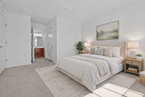 A bedroom with a large bed, a nightstand, and a painting on the wall.