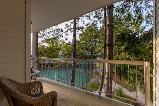 A balcony with a chair and a pool in the background.