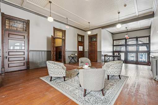 A living room with a grey sofa, a grey armchair, a wooden floor and a rug.
