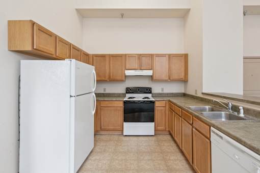 A kitchen with a white refrigerator, black stove, and wooden cabinets.