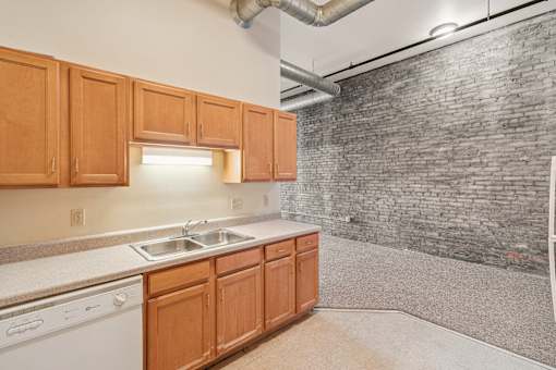 A kitchen with wooden cabinets and a brick wall.