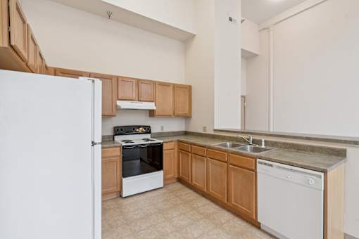 A kitchen with a white fridge, stove, and dishwasher.