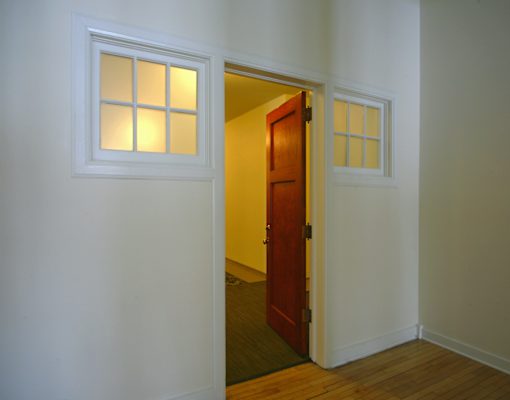A white door with a window above it is open.