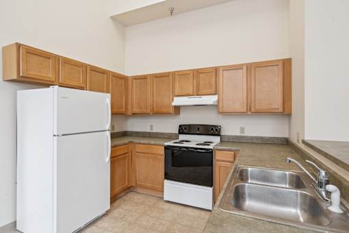 A kitchen with a white refrigerator, stove, and sink.