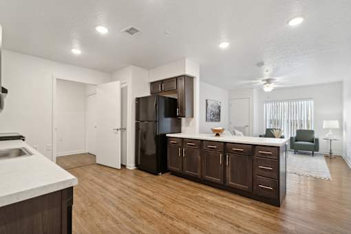 an open kitchen and living room with a refrigerator and a sink