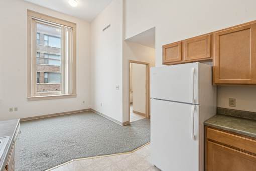 A white refrigerator sits in a kitchen with wooden cabinets.