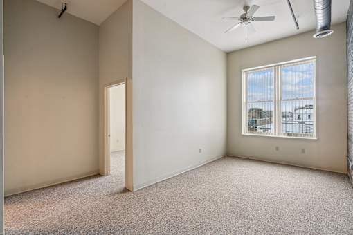 Empty room with a window and a ceiling fan.