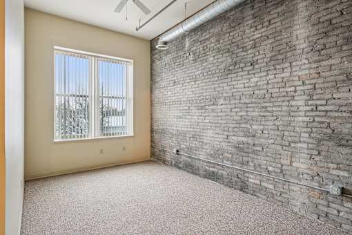A room with a brick wall and a window with a view of trees.