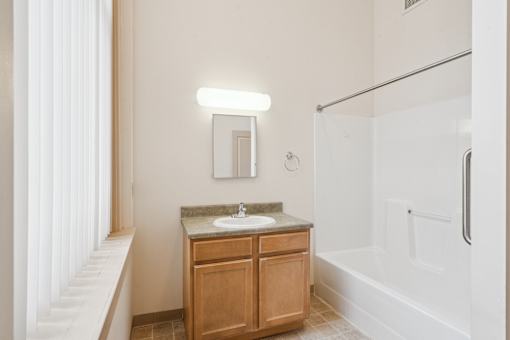 A bathroom with a sink, mirror, and a glass shower stall.