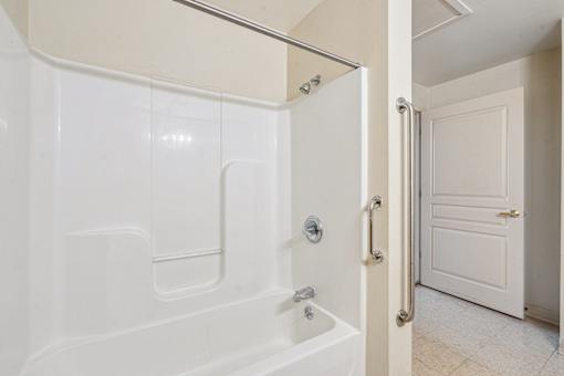 A white bathroom with a tub and a door.