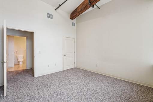 A room with a carpeted floor and a doorway leading to a bathroom.