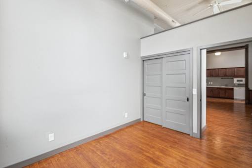 A room with a wooden floor and a white wall with a closed door.