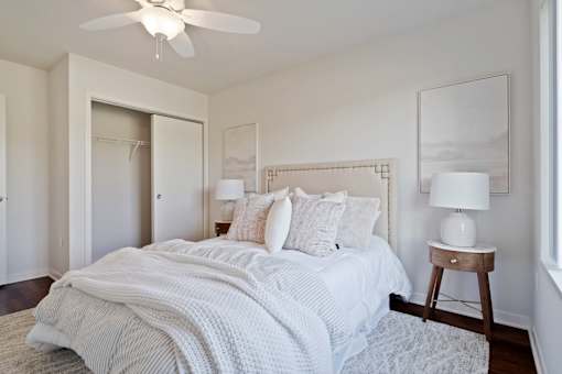 A bedroom with a bed, a ceiling fan, and a chair.