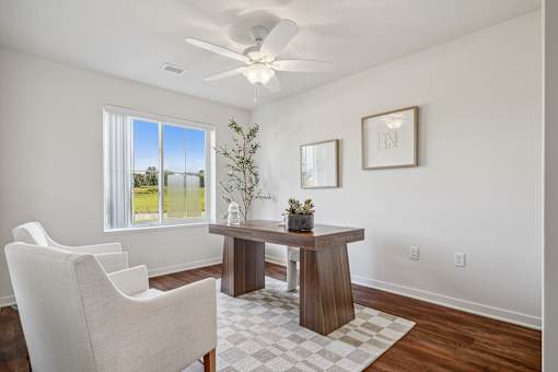 A room with a table, chairs and a ceiling fan.