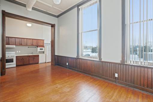 A large empty room with wooden floors and a view of the outside through the windows.