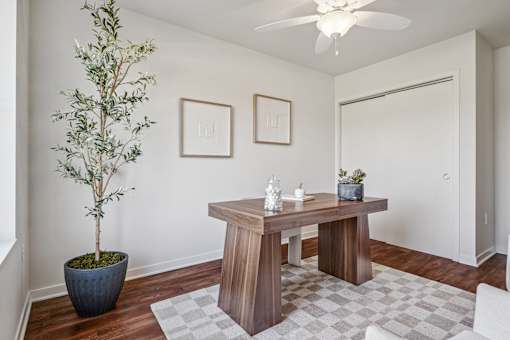 A room with a table, a plant, and two pictures on the wall.