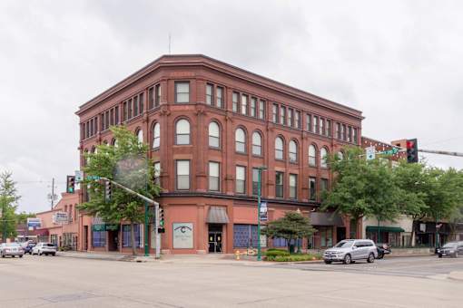 A large red brick building with a green awning sits at a street corner.