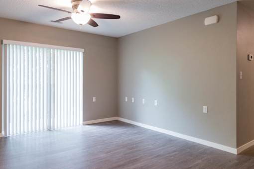 A room with a ceiling fan and a window with blinds.