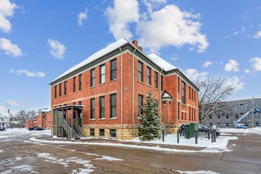 A red brick building with a green door and a tree in front.