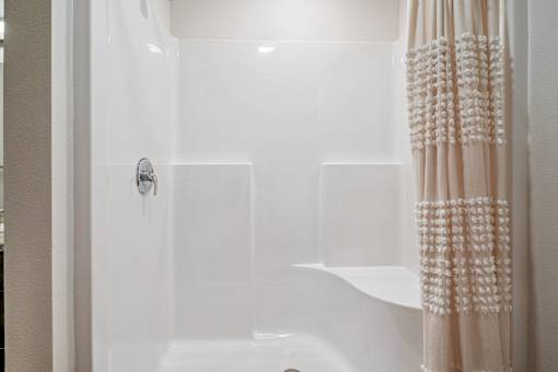 A white bathroom with a shower and a shower curtain.