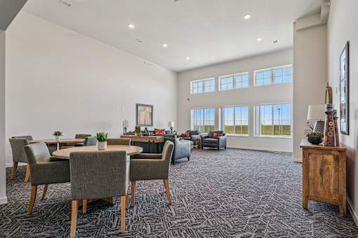 A spacious living room with grey chairs and a carpeted floor.