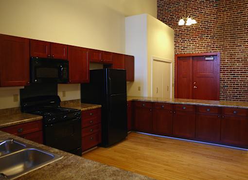 A kitchen with wooden cabinets and a black fridge.