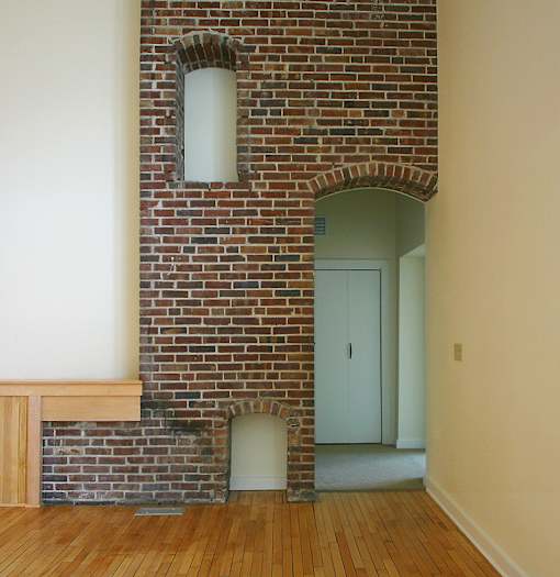 A room with a brick wall and a white door.