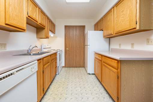 A kitchen with wooden cabinets and a white fridge.