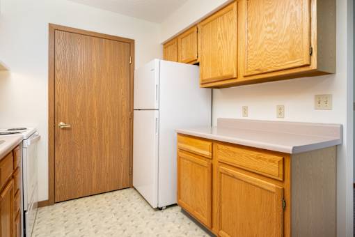 A kitchen with a white fridge and wooden cabinets.