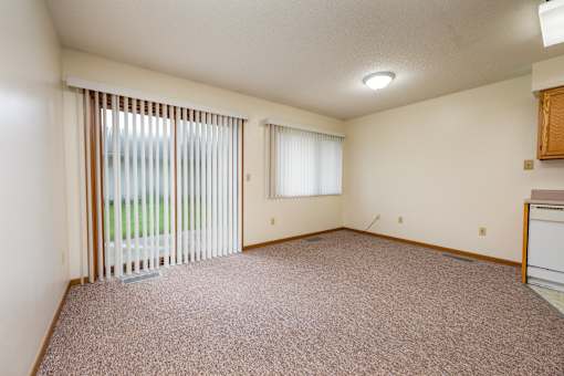 A room with a carpeted floor and a window with blinds.