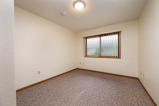 A room with a window and carpeted floor.