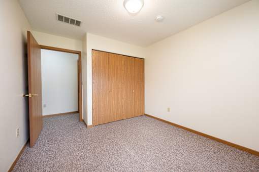 A room with a carpeted floor and two doors.