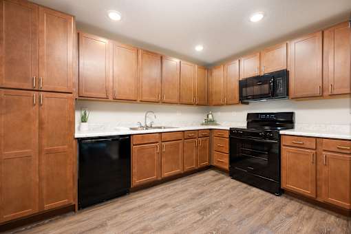 A kitchen with wooden cabinets and black appliances.