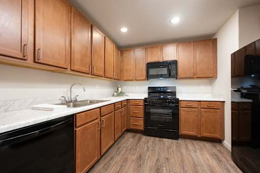A kitchen with wooden cabinets and black appliances.